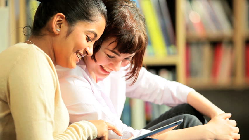 Young female multi ethnic classmates studying knowledge on internet in university information hub