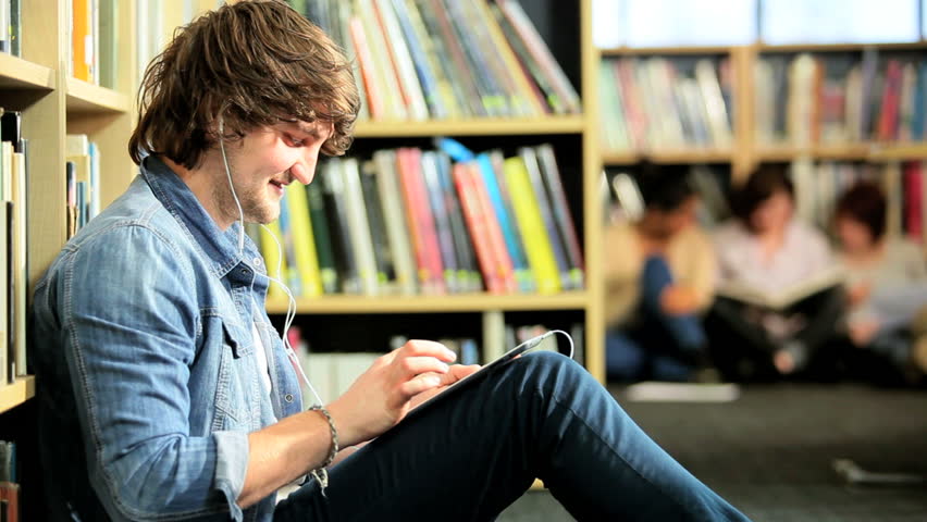 Young male Caucasian classmate using tablet and listening to IT lecture in college hub