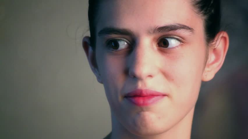 Young adult woman puts her finger to her lips and makes a gesture of quiet.
