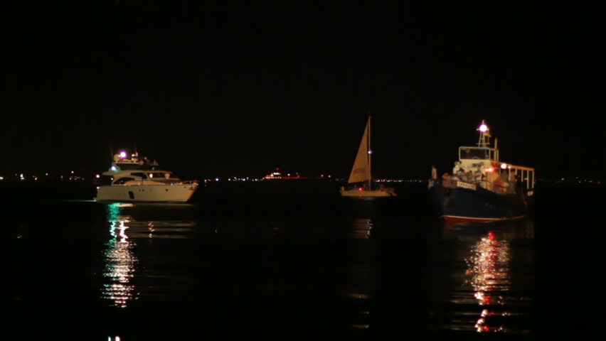 Boats sailing in a harbor at night.