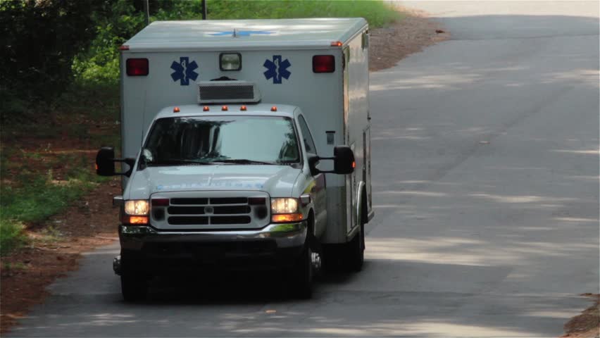 Zoom Close Up of an ambulance emergency driving toward camera.