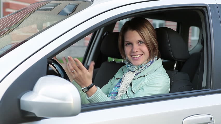 Smiling happy Caucasian woman showing ignition key in new car window