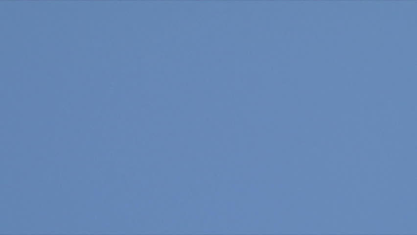 Airplane flies overhead on clear, blue sky day leaving behind vapor trail jet contrails.