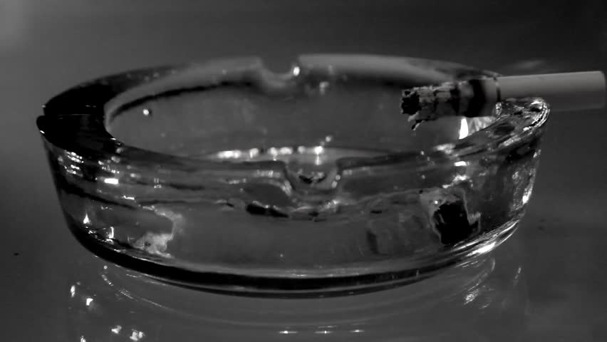 A burning cigarette in an ashtray -black and white 2