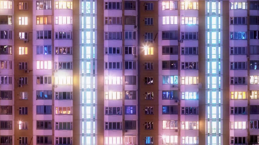Windows of city building illuminated at night. Timelapse.