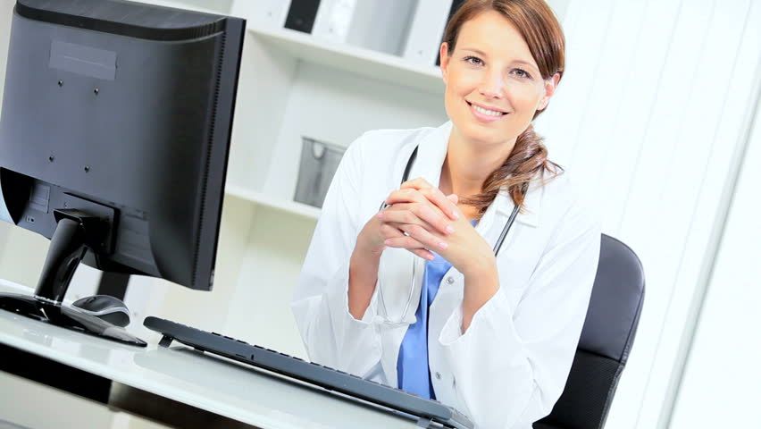 Female Caucasian hospital doctor using computer monitor to access data on clinical trials