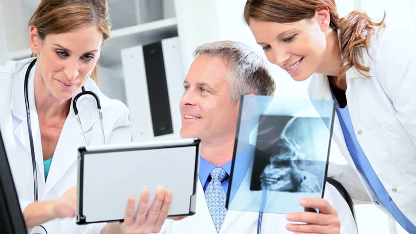 Male female hospital doctors comparing patient x-ray results with wireless tablet
