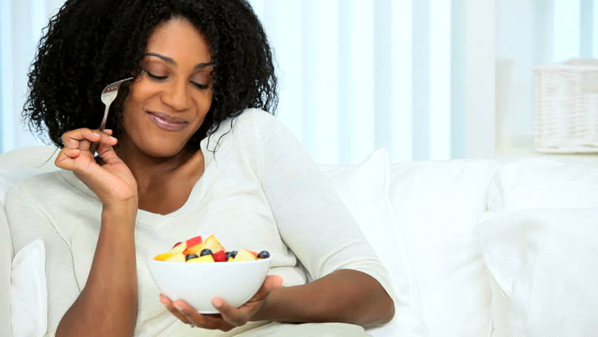 Healthy young African American woman following low fat diet eating fresh fruit
