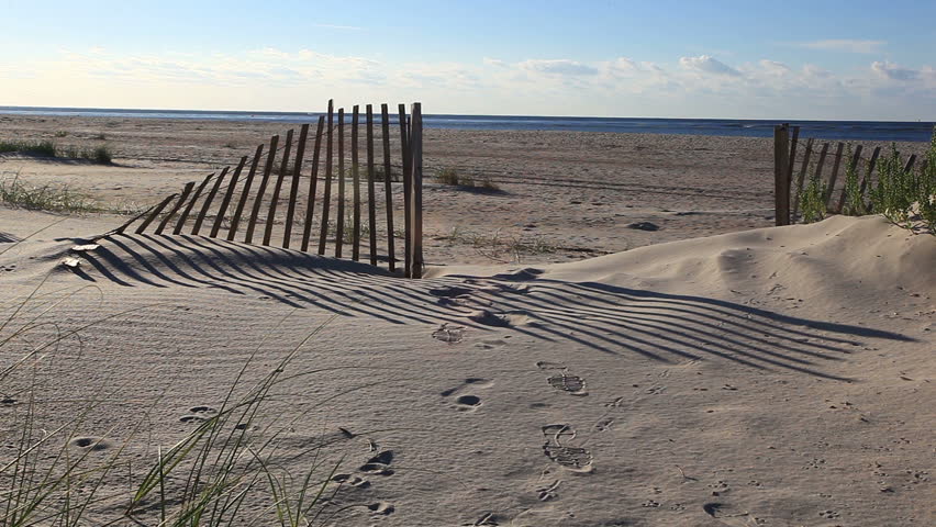 Seeking a seaside escape. (an opening in a sand dune fence leading to a beautiful beach)