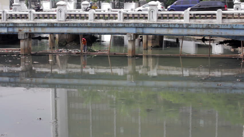 Indonesian man working in unhealthy open sewer of Jakarta