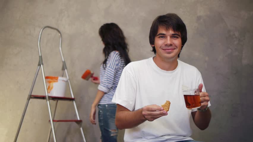 Attractive man drinking tea while his wife working