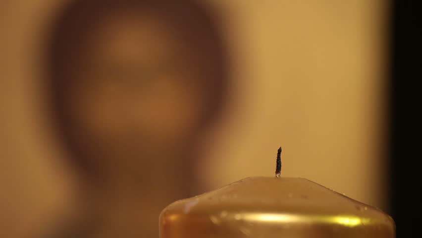 Lighting candle in front of Jesus Christ orthodox icon. Praying moment. 

