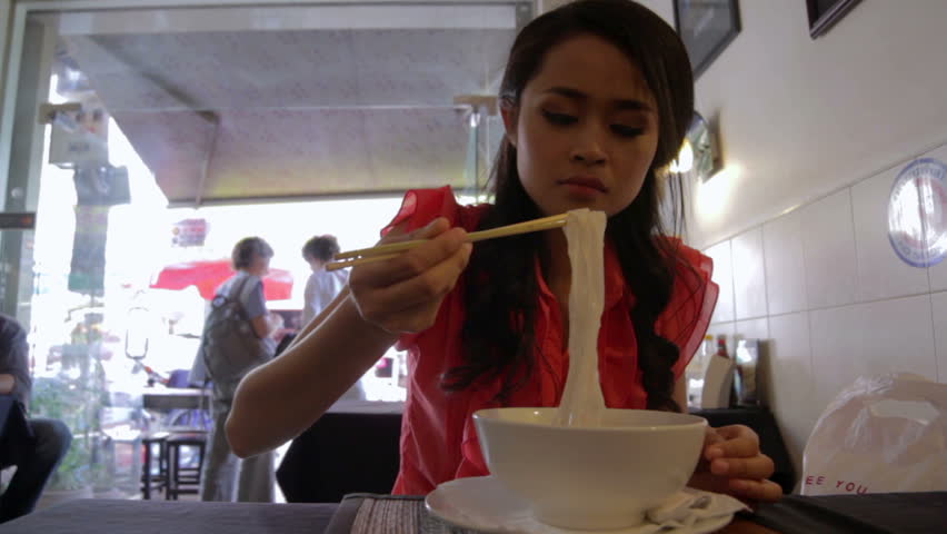 Asian girl eating yummy noodles in a local restaurant, phnom penh