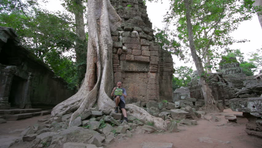 Visitor reading tourist information map in Ta Prohm temple, Angkor