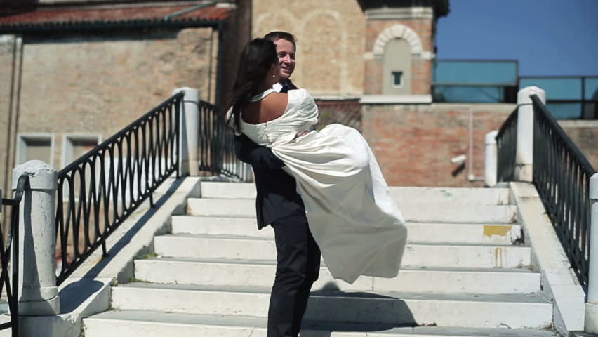 Happy just married groom carry on his hands the bridge in Venice
