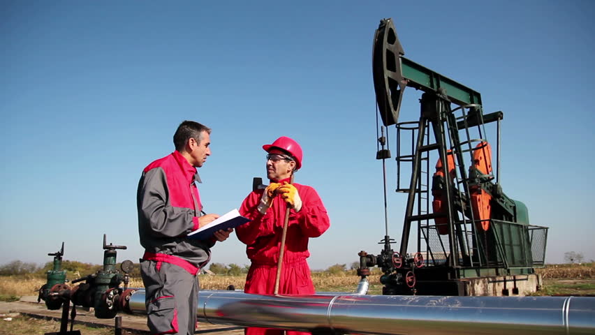 Two Workers in front of Oil Well.
Engineer giving orders to oil worker. HD1080p.
