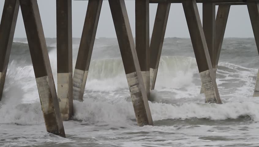 Medium Close Clip Atlantic Ocean Waves Crash into Johnny Mercer Pier Wrightsville Beach North Carolina as Hurricane Sandy Passes Along the Coast.  Waves spray up as they hit the pilings of the pier. 