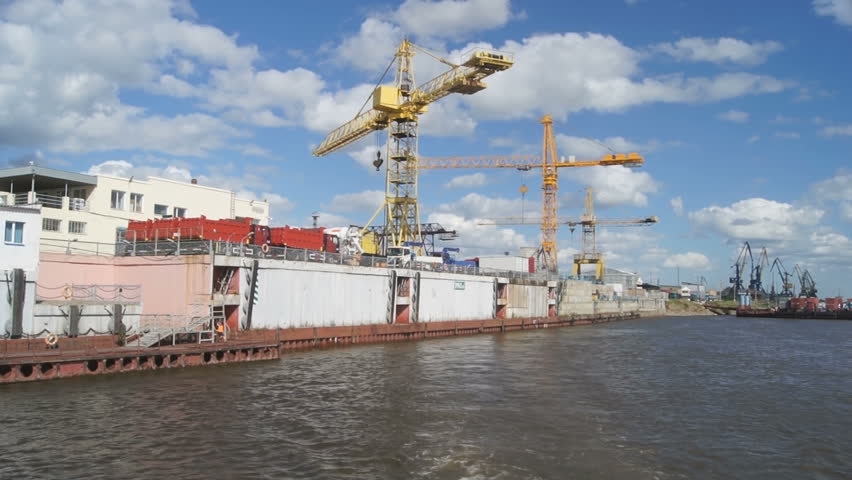 View of the Russian city of Blagoveshchensk from the boat, floating on the river Amur. Pan left: berth, coastline, actual buildings, river fairway, on a background of cloudy sky. Summer 2012.