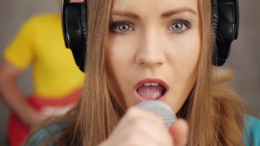 Pretty woman singing song and recording in music studio