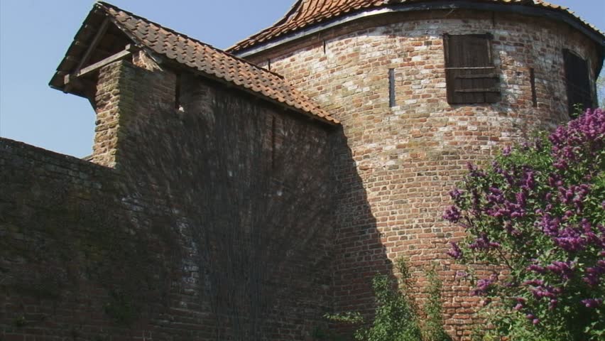 ZUTPHEN, THE NETHERLANDS - APRIL 2011: 14th century city wall with round tower - pan Syringa vulgaris