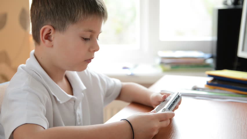Child plays a portable electronic game. Dolly shot