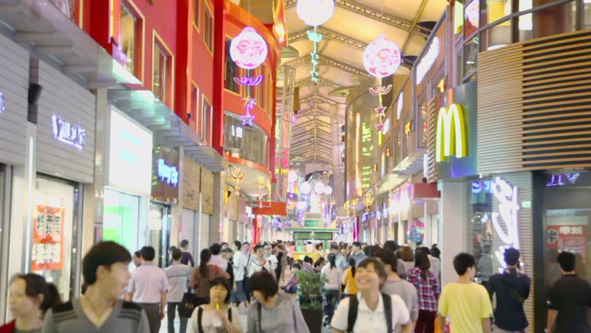 GUANGZHOU - NOV 20: Lot of people walk by street with illuminated showcases of shops and cafes on Nov 20, 2011, in Guangzhou, China. Guangzhou population density is 1883 people per sq. km.