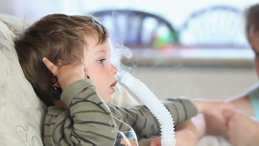 Mother and little boy using nebulizer to inhale medicine panning