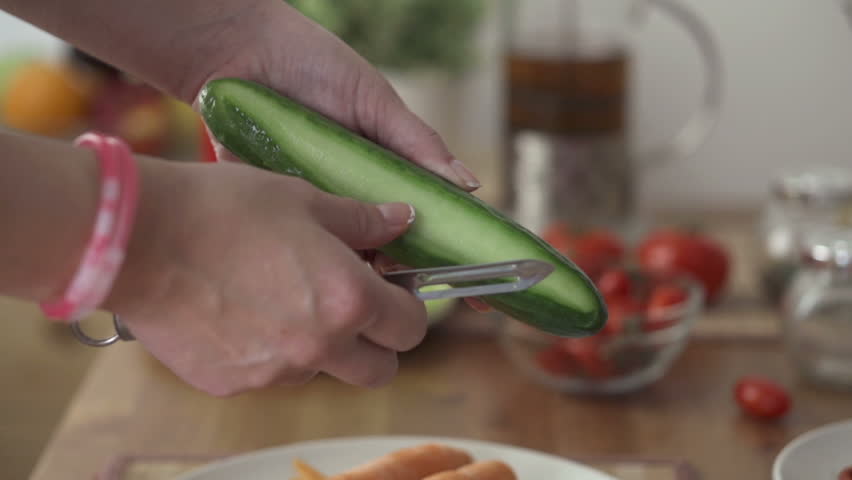 Female hands peeling cucumber
