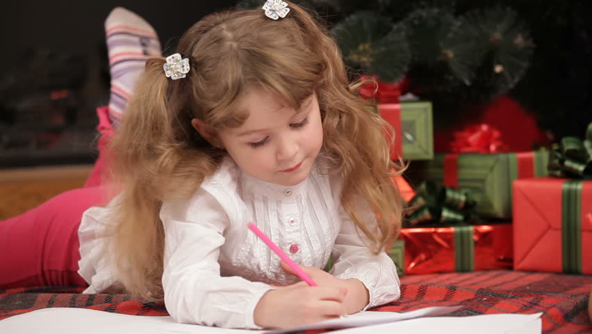 A girl seating near a Christmas tree and drawing.
Expecting Christmas.