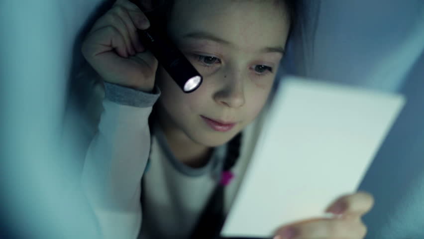 Girl under the covers with a flashlight