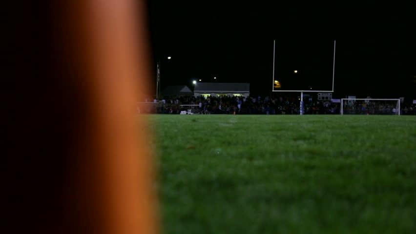 Nigh time dolly of a football field revealed behind a pylon.