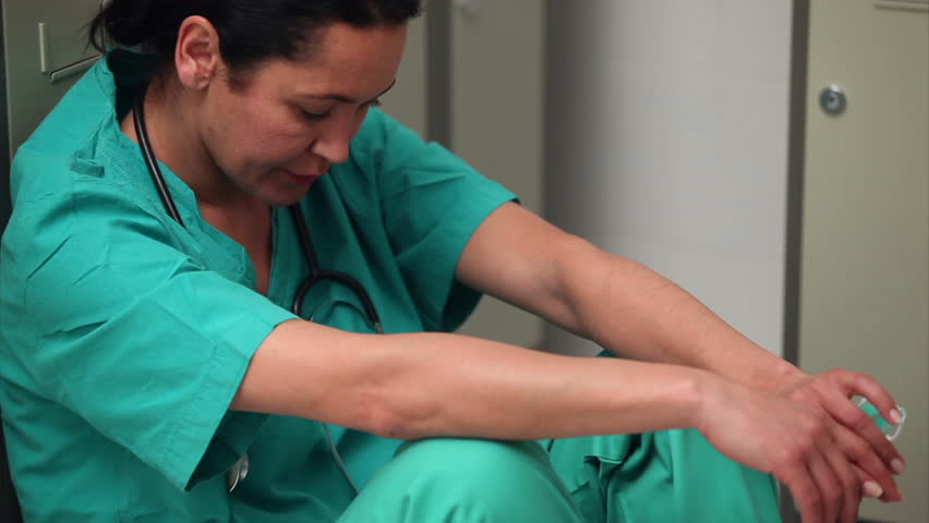 Thinking female surgeon sitting in a locker room in a hospital