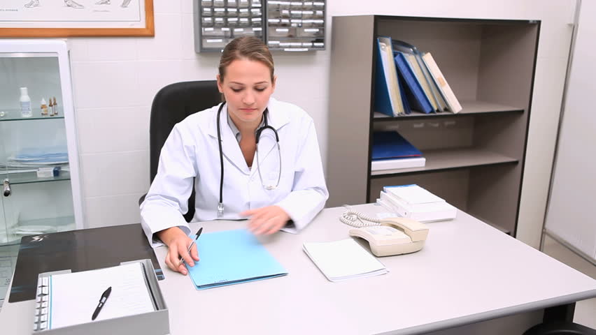 Doctor writing on a notepad at his desk in a medical office
