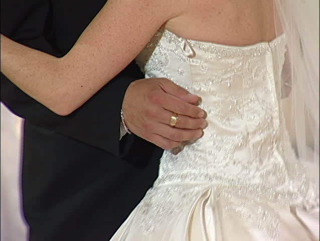 Groom embraces bride in dance