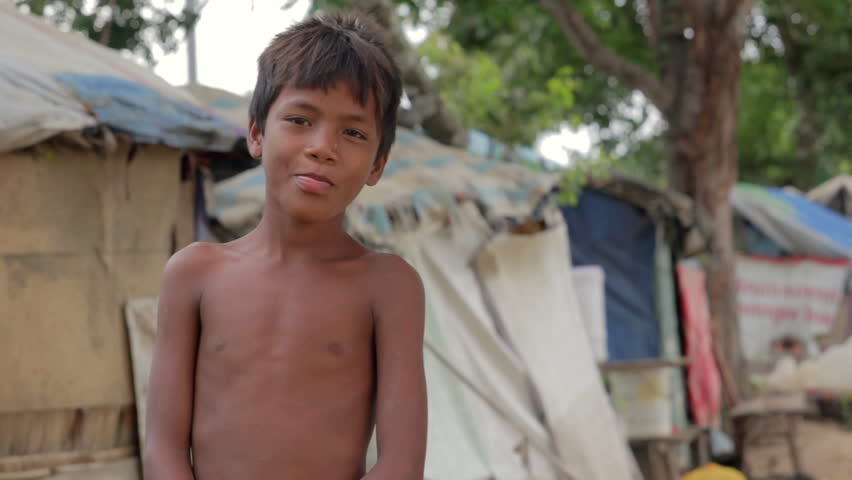 Cambodian boy in slum, shacks at background