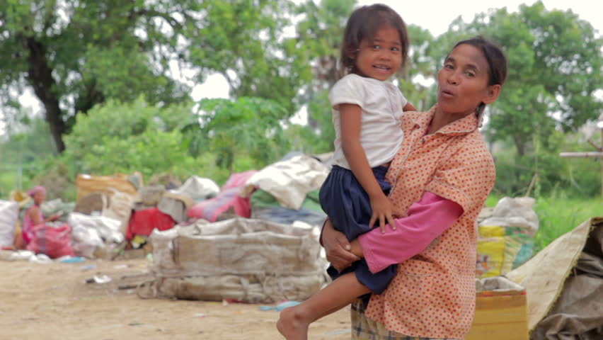 Mother holding baby in Cambodian shanty, close dumping area
