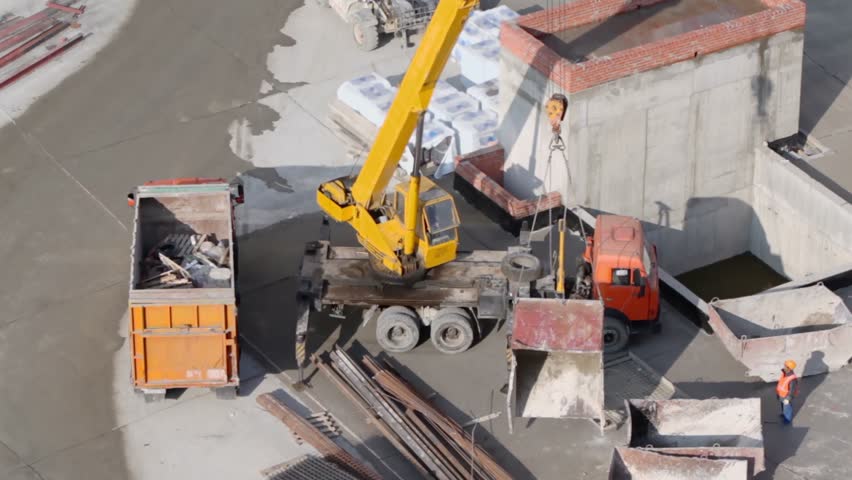 Labourers use crane to load lorry, view from above at building site
