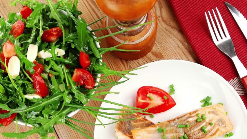 savory sea fish : baked salmon strips with green vegetable salad and tomatoes red caviar in white bowl grinder and cutlery on wooden table