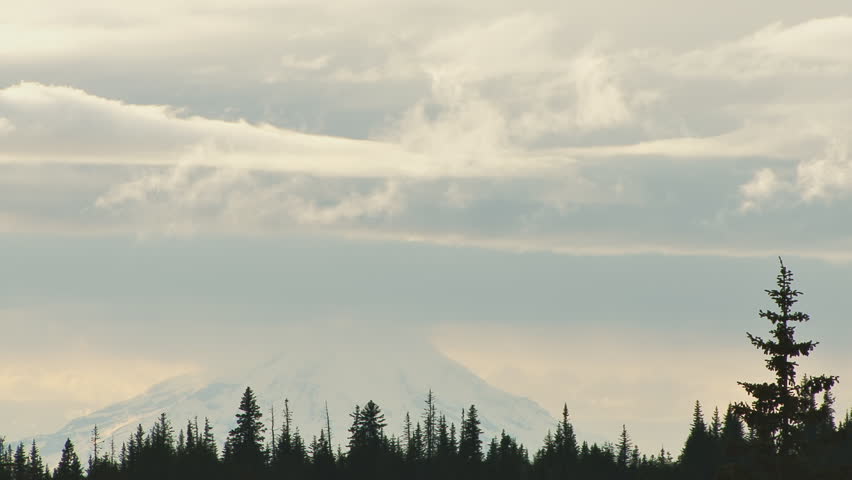 Luminous, multi-layered clouds moving over a distant volcano "Mt. Redoubt", in Alaska. Moderate time lapse.