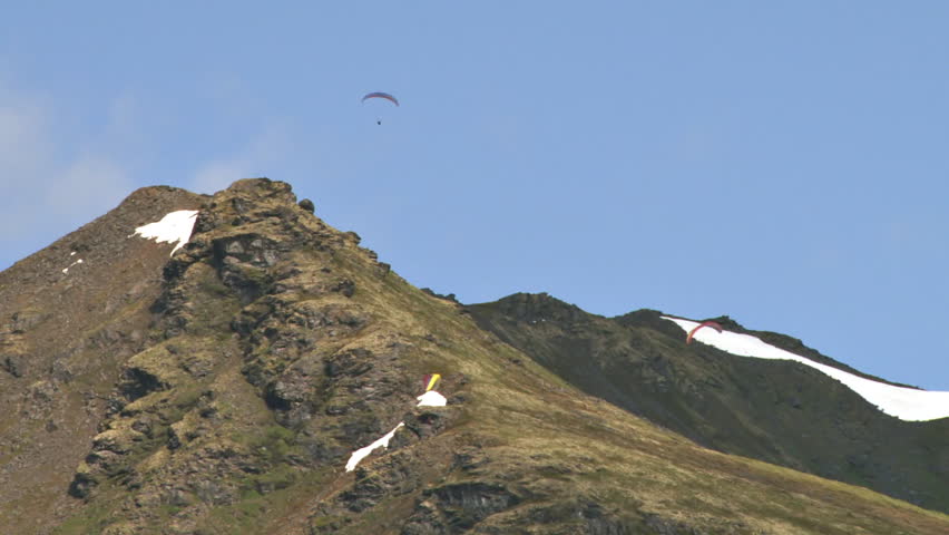 Several paragliders soaring gracefully on updrafts in the Talkeetna Range of Alaska, at Hatcher Pass.