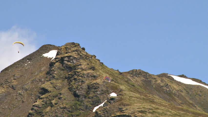 Paragliders soaring gracefully above the mountain ridges of Hathcer Pass in the Talkeetna Mountain Range in Alaska.