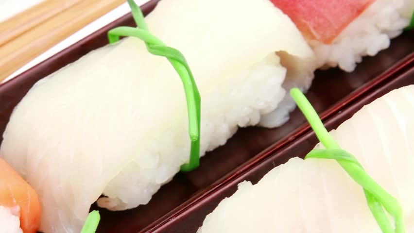Japanese Cuisine - Different Types of Nigiri Sushi : Tuna (maguro) Salmon (sake) and Eel (unagi) with Wasabi and Ginger on bamboo mat isolated over white background