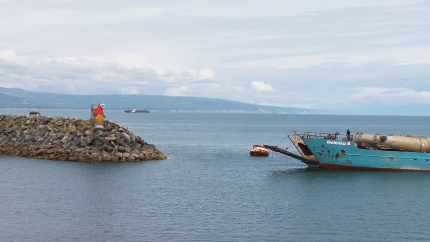 HOMER, AK - CIRCA 2012: A weatherworn landing craft on approach to the harbor with its cargo of a diesel tractor truck and four tank trailers.