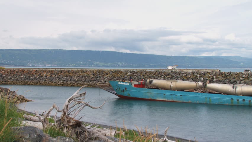 HOMER, AK - CIRCA 2012: A weatherworn landing craft on approach to the harbor with its cargo of a diesel tractor truck and four tank trailers.
