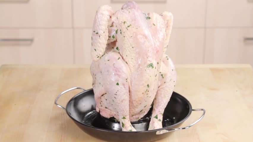 Shallots with olive oil and rosemary being added to a chicken roaster