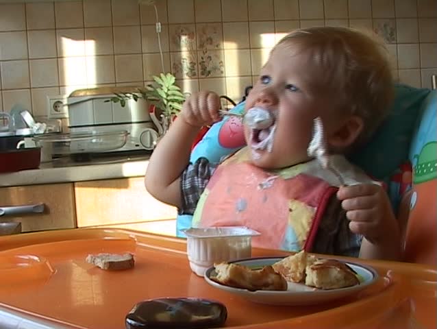 Baby learning to feed himself with a spoon and getting messy in the process