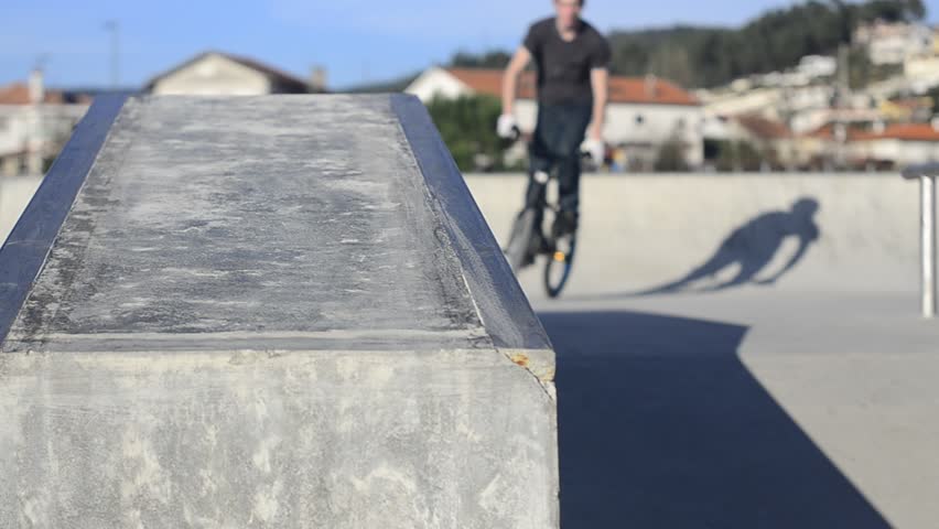 Bmx rider grinding on a concrete park on a sunny day.