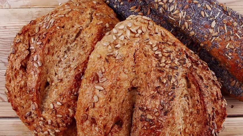 delicacy french rye breads and baguettes topped with sunflower and poppy seeds over wooden table