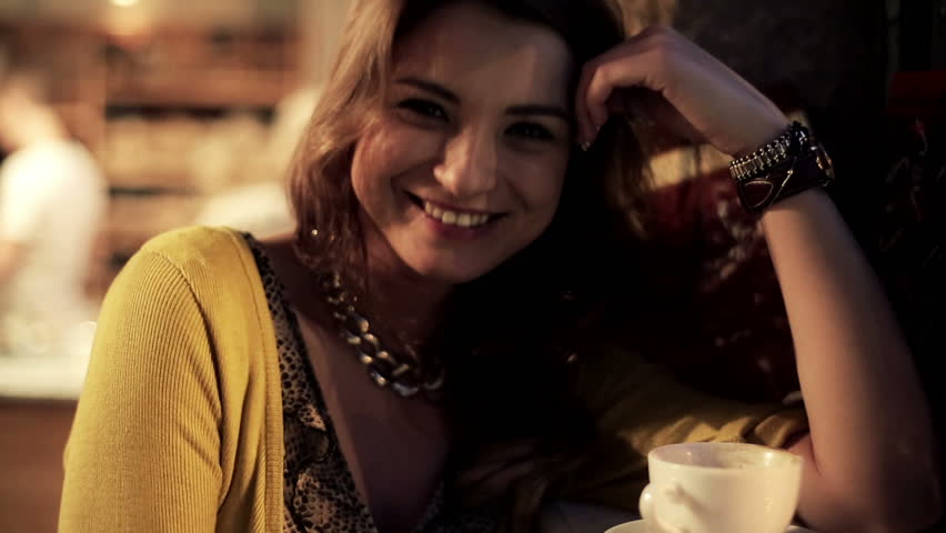Young attractive woman smiling to camera in cafe, steadicam shot