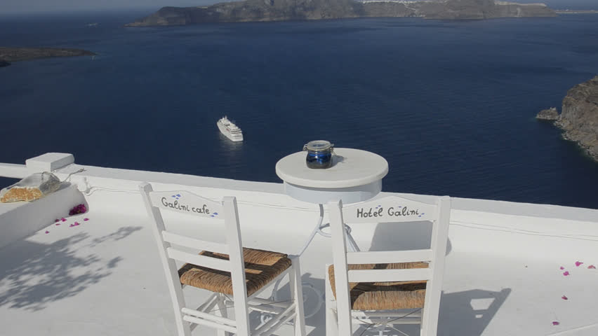 Postcard scene of two lonely chairs on terrace with table ready for tourists in Santorini Greece in Greek Islands